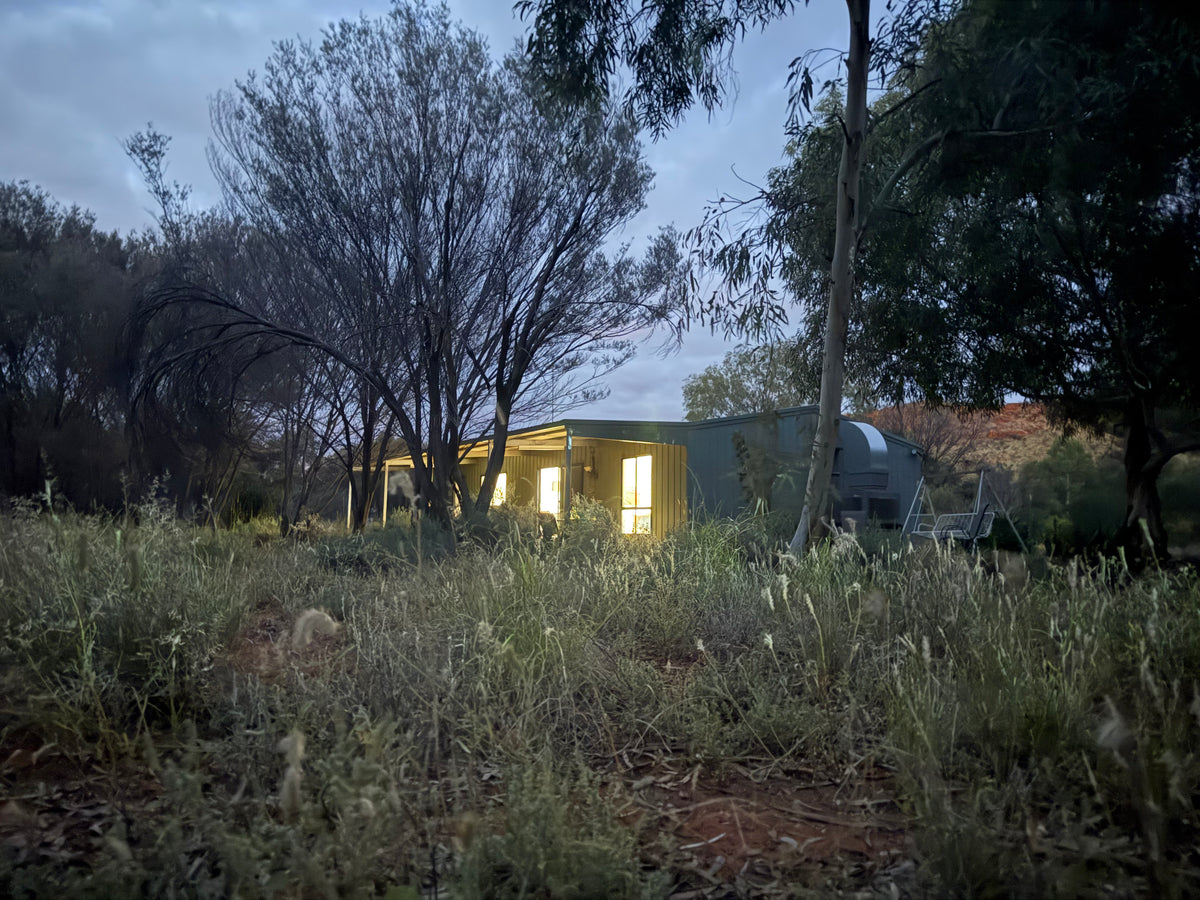 Cabin in the bush at night with lights on